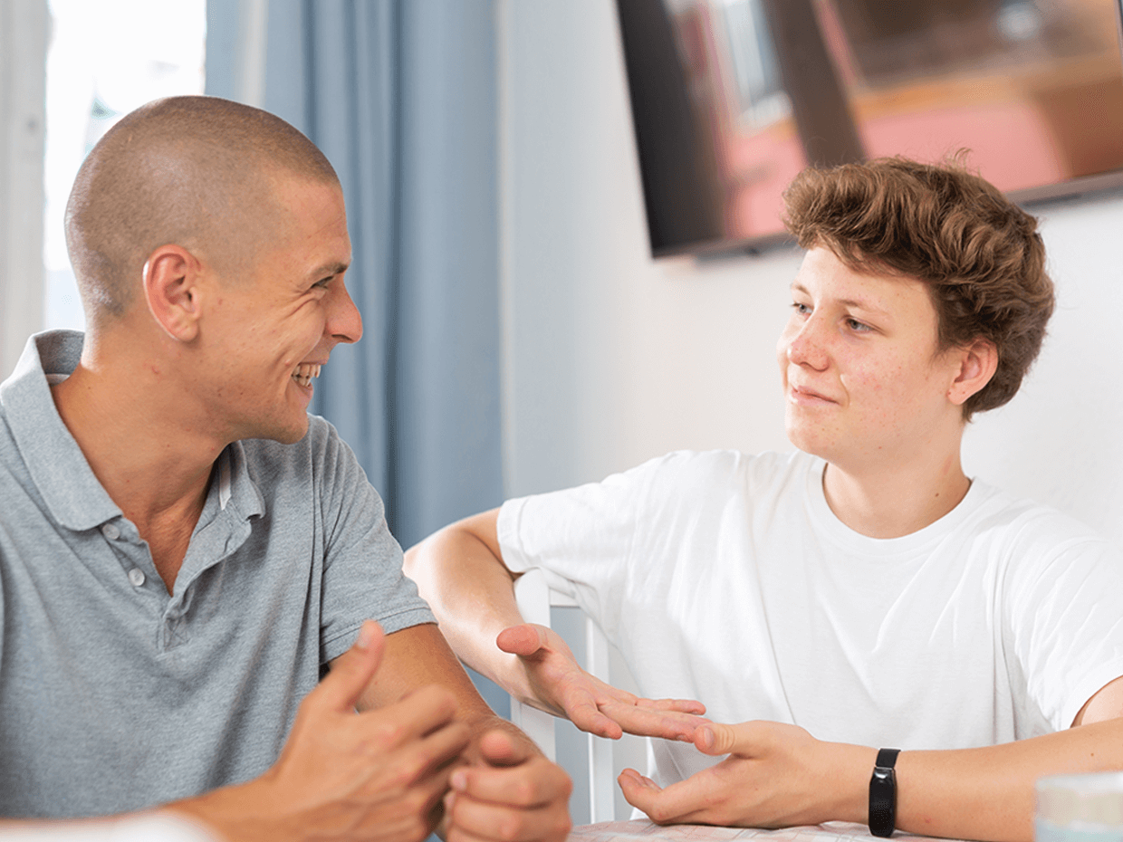 An image of a father and son conversing at a dinner table